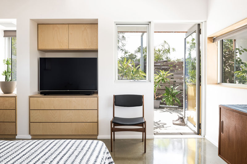 This bedroom has custom cabinetry that's built into an alcove, while a glass door opens to a private patio area. #Cabinetry #Bedroom