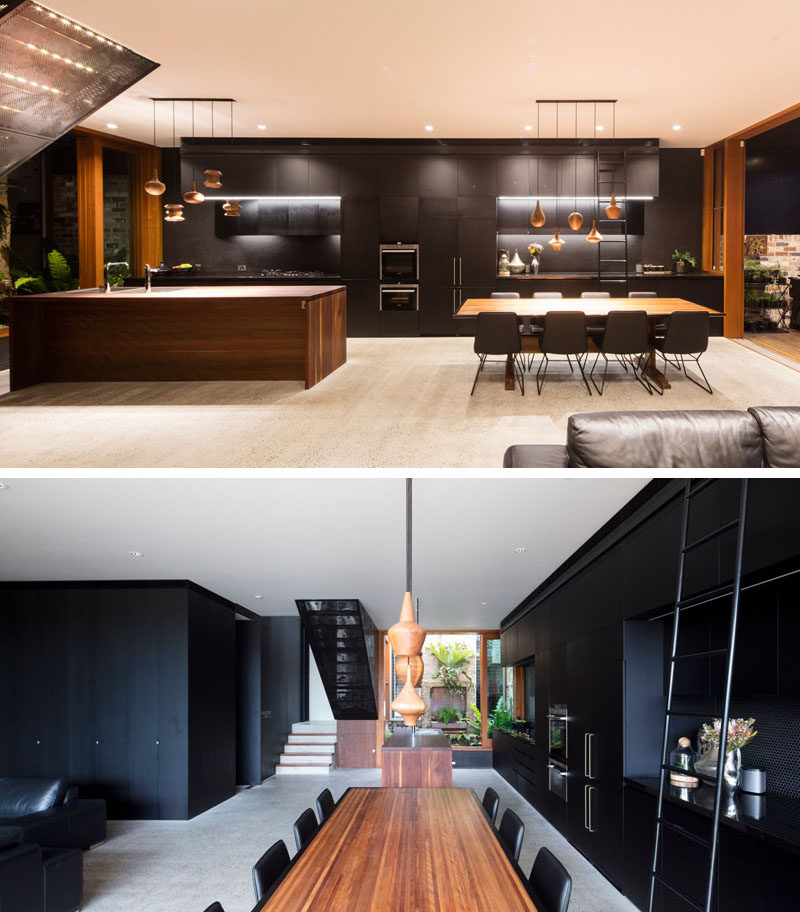 In this modern interior, black cabinetry runs the length of the wall, from the kitchen through to the dining area. #BlackCabinetry #InteriorDesign #BlackInterior #BlackAndWood