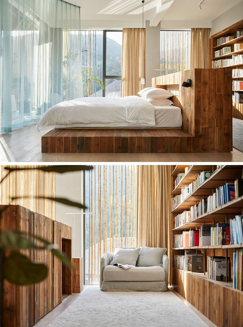 This modern hotel room has a centrally located bed that has a large wood bed frame and headboard. Behind the bed is a wood bookshelf and a small reading area. #HotelRoom #Bedroom #Bookshelf #BedFrame