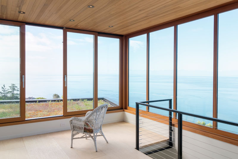 This modern house has an art studio at the top of the house, with walls of windows, and a door that opens up to a green roof. #Windows #GreenRoof