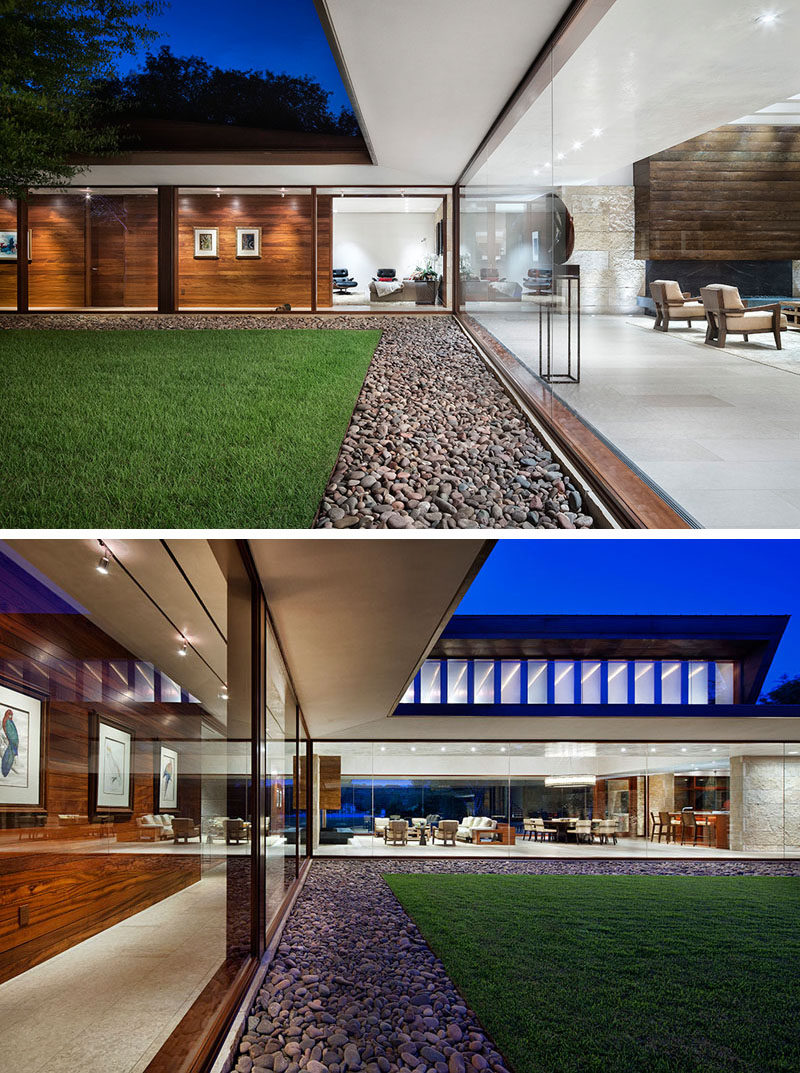 This modern house has a front lawn that's surrounded by a border of smooth pebbles, while large glass walls provide a glimpse inside. #GlassWalls #Landscaping #Lawn