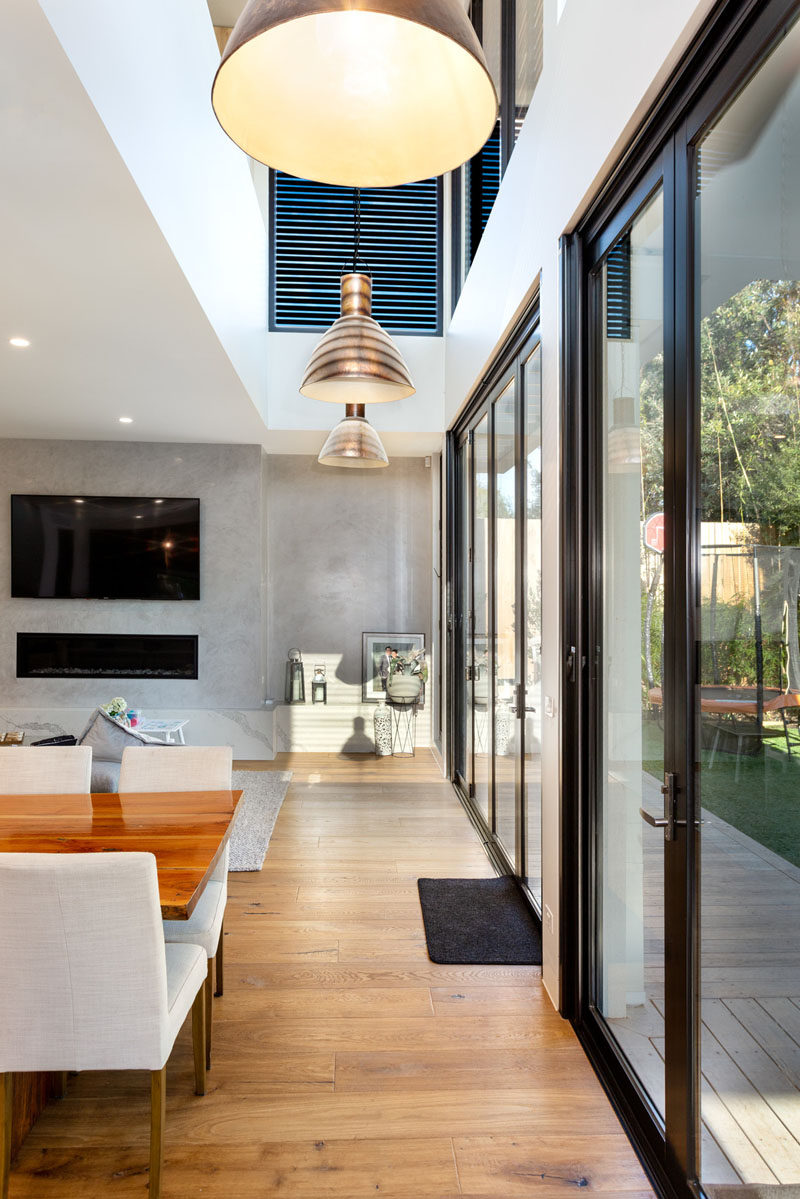 A wall of glass doors opens the interior of this modern house to the backyard, creating an indoor/outdoor environment and extending the available area for entertaining guests. #GlassDoors #InteriorDesign