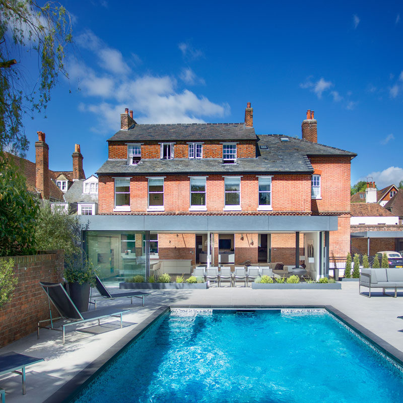 This modern extension is clad in dark-grey fibre-cement board, chosen for its clean character and large format, and its ability to match the tone and color of the existing slate roof. #ModernExtension #Architecture #SwimmingPool