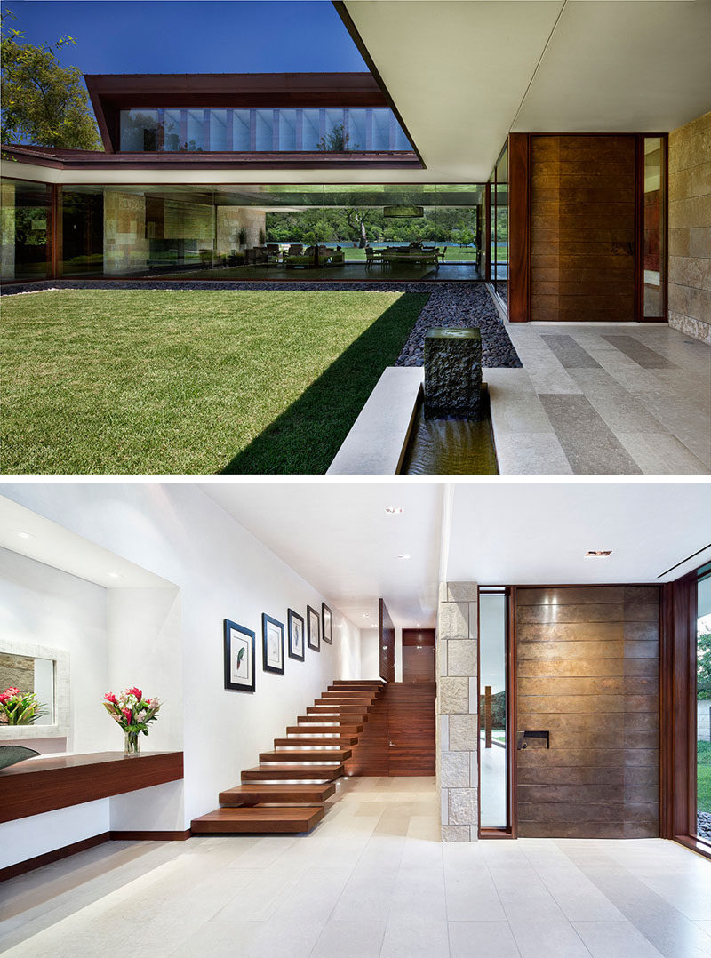 This modern house has a custom front pivot door that's clad in copper. It opens to a foyer with honed limestone flooring, that's also featured throughout the home. #PivotingFrontDoor #CopperDoor #LimestoneFlooring