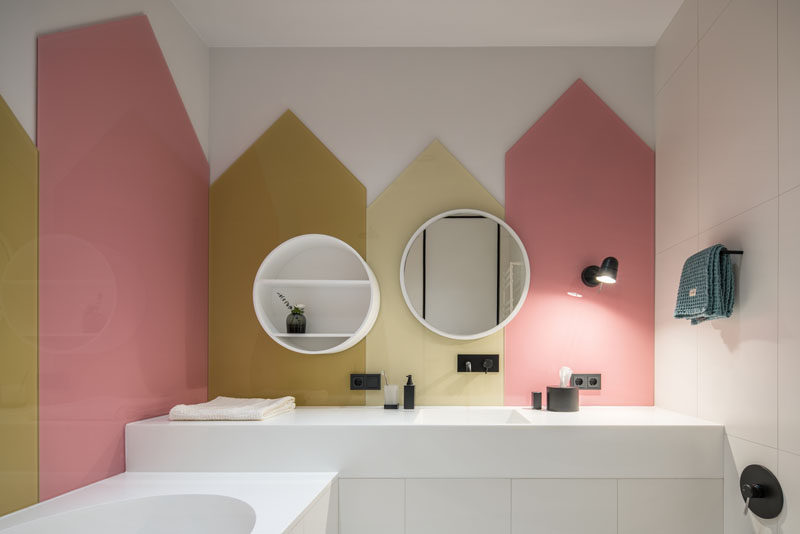 Colored glass panels in the shapes of little houses cover the walls of this kids bathroom.