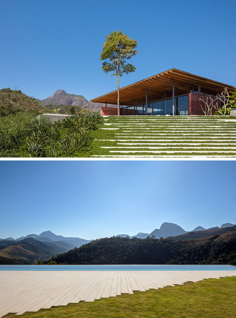 Surrounded by mountains and situated on a sloped lot, this modern house has landscaping that makes it easy to enjoy the views, including a large patio that meets an infinity edge swimming pool. #ModernHouse #Landscaping #SwimmingPool