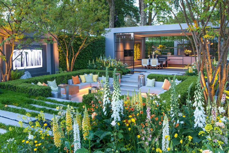 This garden features a sunken patio area with built-in seating, and a pavilion that houses a dining area and kitchen. #Landscaping #LandscapeDesign #Garden #Backyard