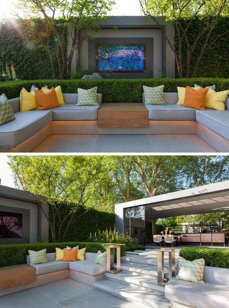 This modern garden features a sunken patio with built-in seating is surrounded by box-hedging, while stone steps leading up to a pavilion with a dining area and kitchen. #Landscaping #OutdoorSeating #SunkenLounge #GardenDesign