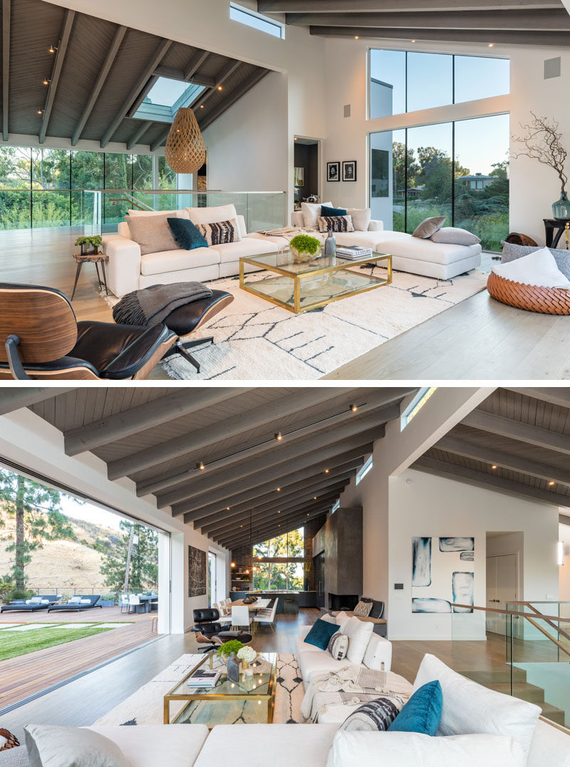 This large and open modern interior features a vaulted ceiling, plenty of windows, while white oak flooring, and a wall of glass that opens to the backyard. #ModernLivingRoom #InteriorDesign #Windows #VaultedCeiling