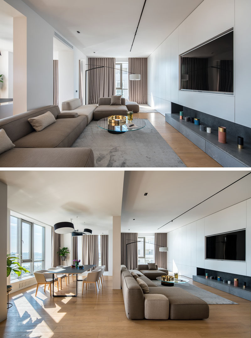 This open living area is long, with the couches focused on the television, and a window at the end of the room adds natural light to the space. #LivingRoom #InteriorDesign #ModernLivingRoom