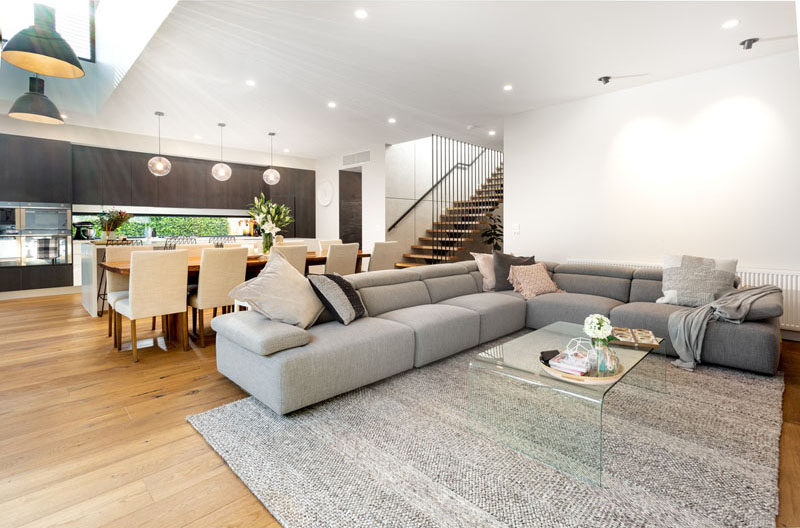 Inside this modern house, the main social areas are all located in a large single room, that features a vaulted ceiling. #ModernInteriorDesign #LivingRoom