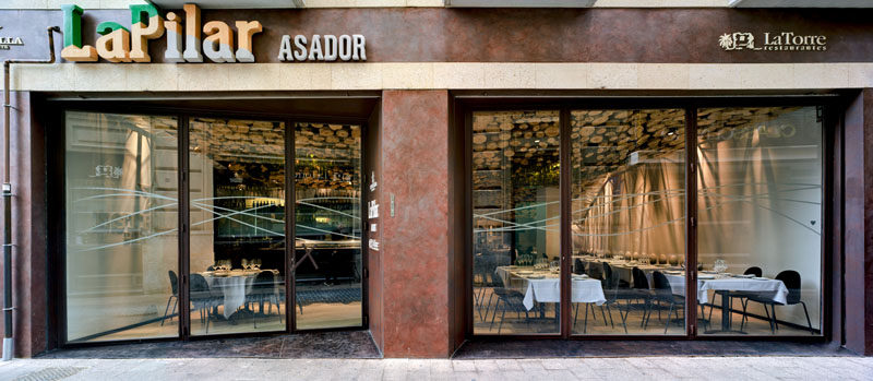 A wavy installation of cut logs and green glass cover the ceiling of this modern restaurant. #Ceiling #Restaurant #RestaurantDesign #InteriorDesign