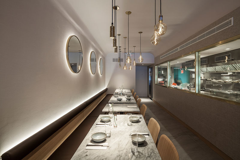 At the rear of this modern restaurant, white walls are highlighted by hidden lighting behind the banquette and the mirrors. #Restaurant #RestaurantDesign