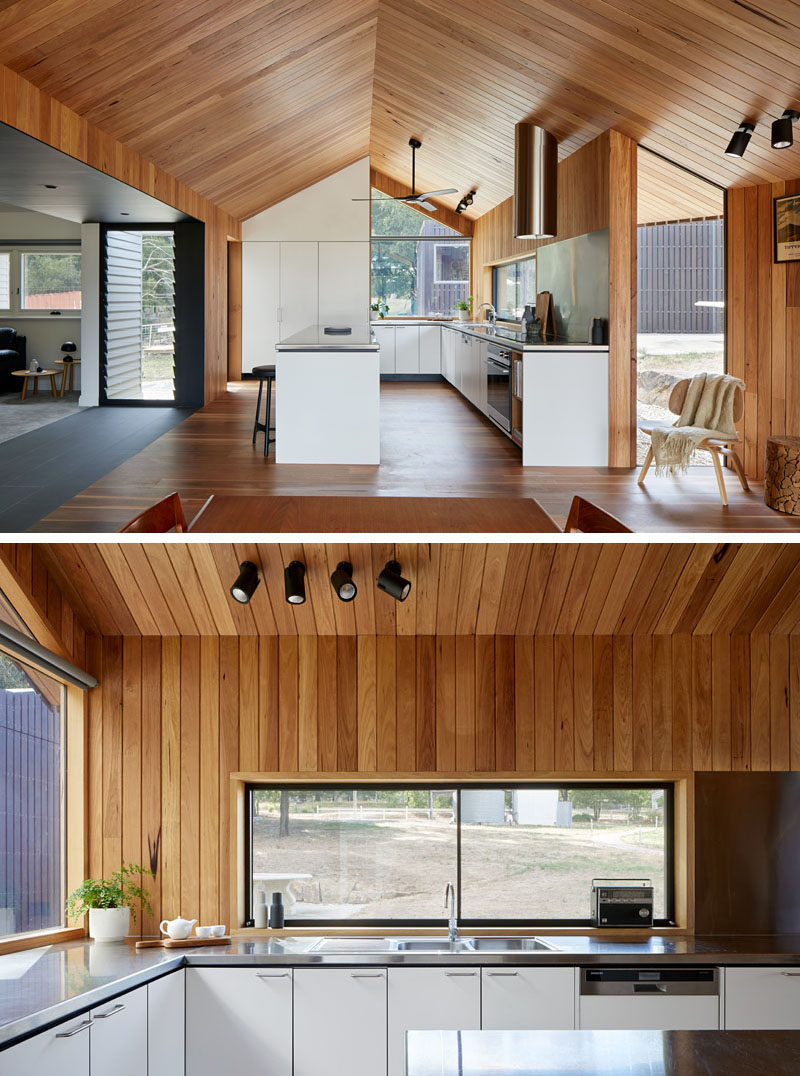 This modern wood-lined interior houses a new white kitchen with stainless steel countertops. #WhiteKitchen #StainlessSteelCounter #GabledCeiling #WoodInterior