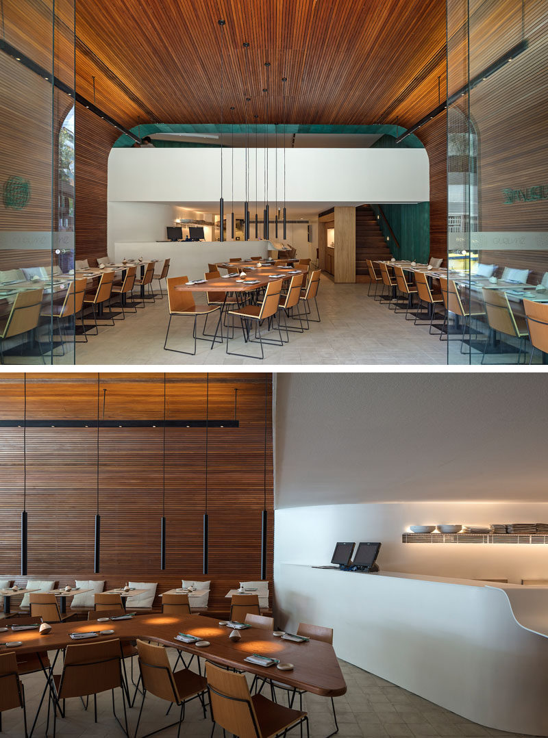 The main room of this modern restaurant is a large and vaulted space that's covered in wood slats. #WoodSlats #RestaurantDesign #InteriorDesign #ModernRestaurant