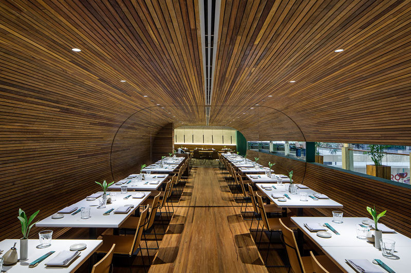 This modern restaurant has dining room lined with wood slats, creating a tunnel like appearance. #RestaurantDesign #RestaurantInterior #ModernRestaurant #InteriorDesign