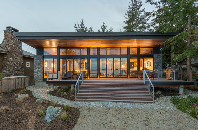 The ceiling of this modern waterfront cottage continues from the inside to the outside, creating a shaded deck for outdoor dining and relaxing. #Architecture #ModernCottage #Roof #WoodCeiling