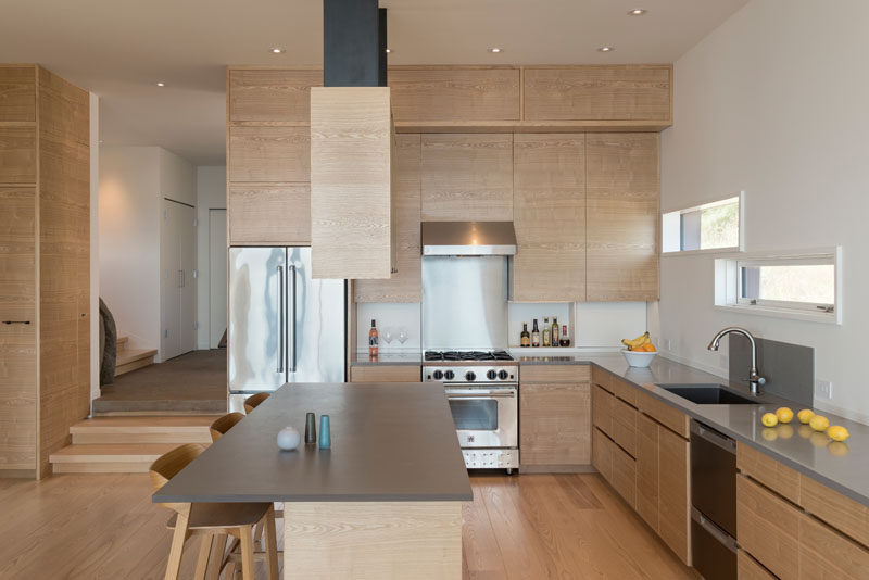 This kitchen combines wood cabinetry with a grey countertop, for a simple and contemporary appearance. #KitchenDesign #WoodKitchen