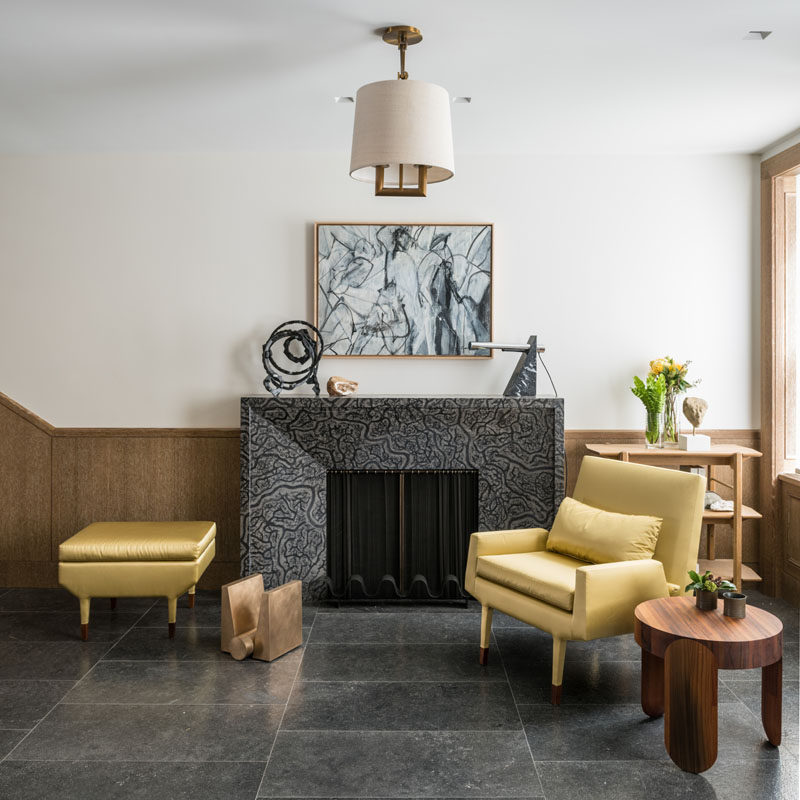 In this contemporary foyer, there's a simple sitting area next to a fireplace. Windows that look out onto the street, fill the space with natural light. #SittingRoom #Foyer #Fireplace