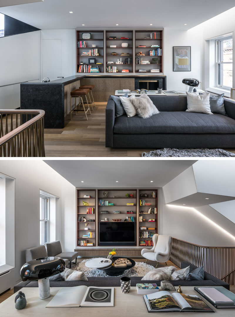 A brushed granite bar and fireplace with faceted geometries anchors this contemporary home library, where custom lacquered steel shelves are featured on both walls. #HomeLibrary #Bar #Shelving #InteriorDesign