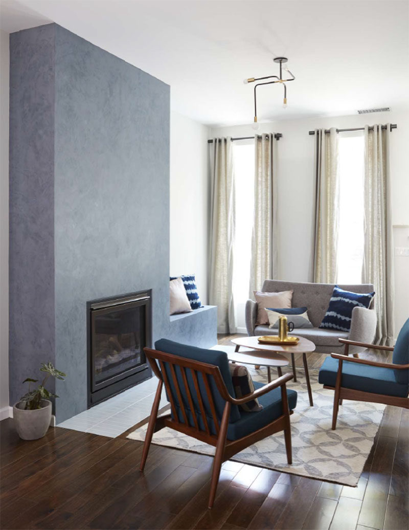 This contemporary living room features a floor-to-ceiling fireplace surround with a built-in bench. #FireplaceSurround #Fireplace #Bench #LivingRoom