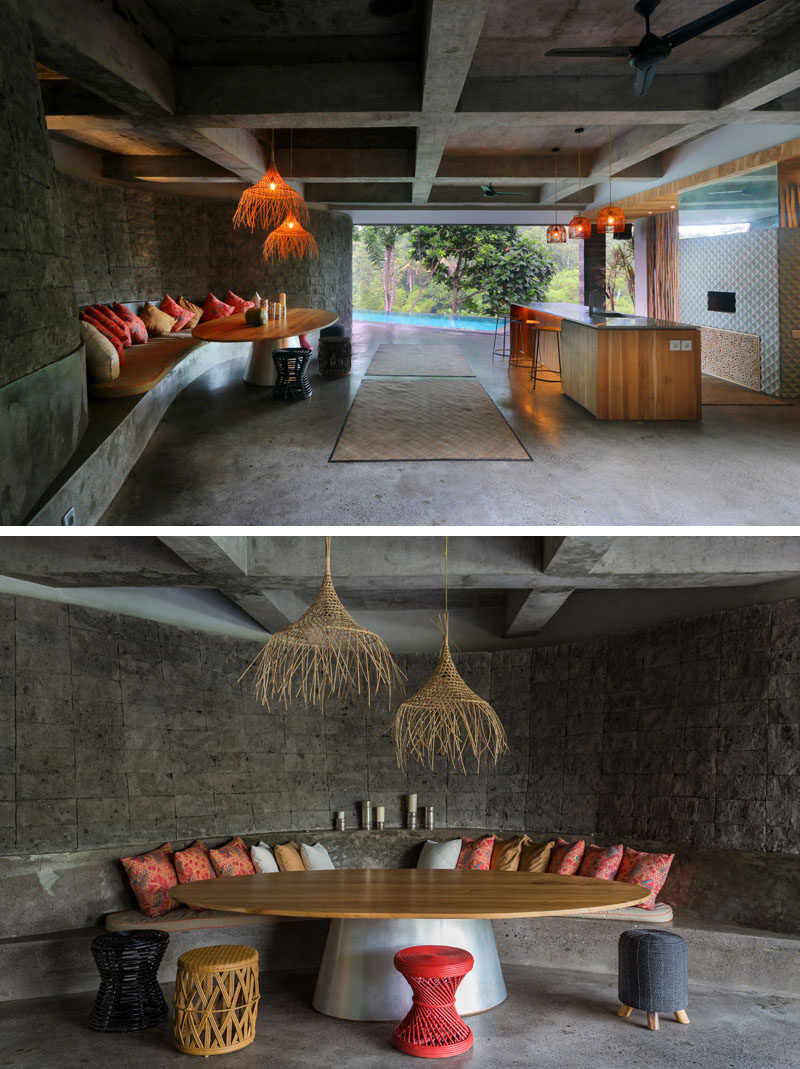 This modern house has a cave-like lounge and bar area that leads to the swimming pool. The lounge features a built-in curved concrete couch with cushions and a large table. #Bar #OutdoorLounge #SwimmingPool