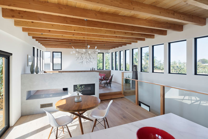 In this open floor plan, a double sided low fireplace connects and organizes the split level dining area and living space, while also allowing for warmth. #InteriorDesign #SplitLevel #Fireplace #ExposedCeiling