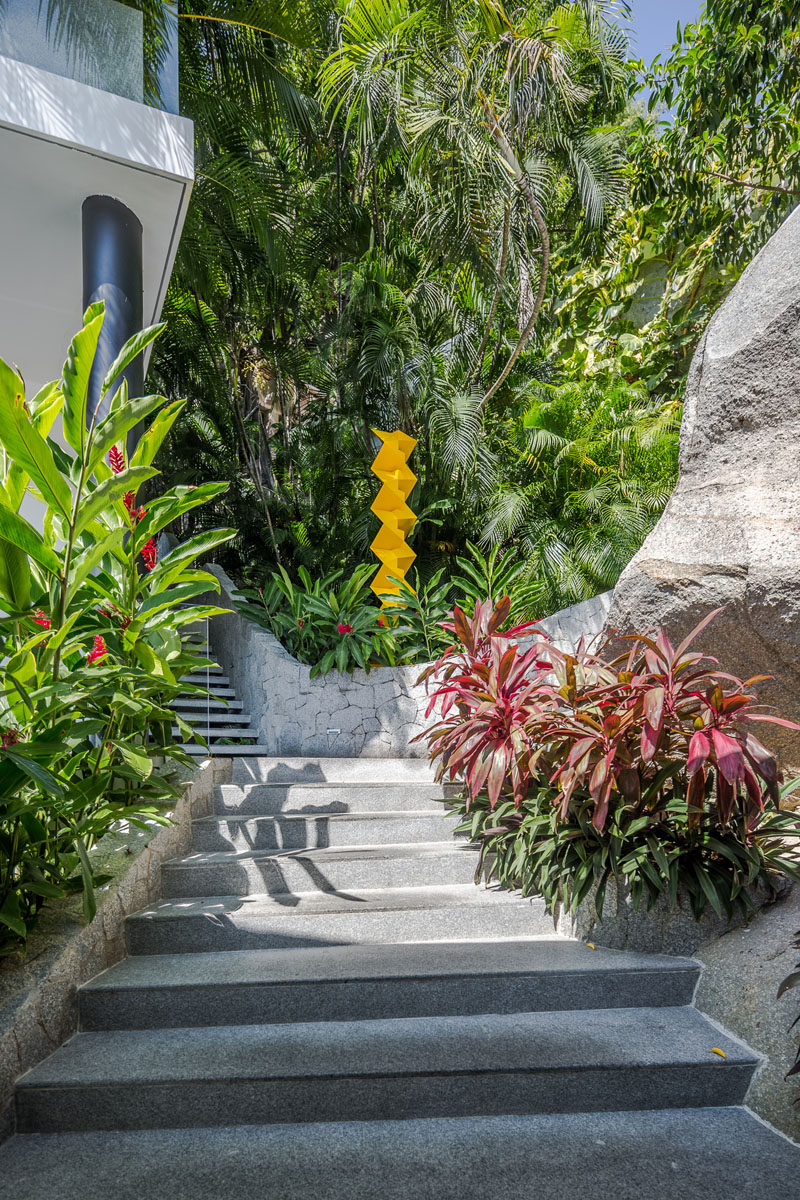 Stairs surrounded by lush landscaping connect the various areas of this modern house. #ExteriorStairs #ModernLandscaping #OutdoorStairs