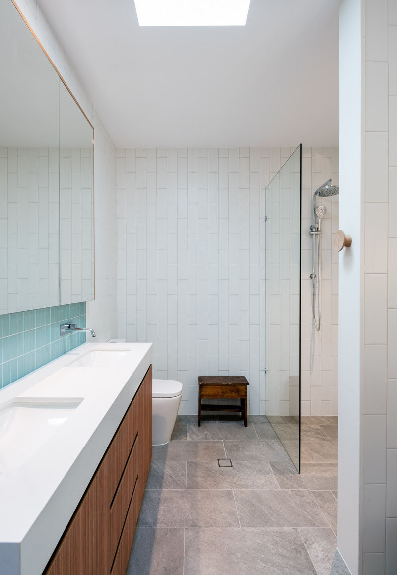 In this modern master bathroom there's a walk-in shower with a glass shower screen. A skylight helps to keep the bathroom filled with natural light. #BathroomDesign #ModernBathroom