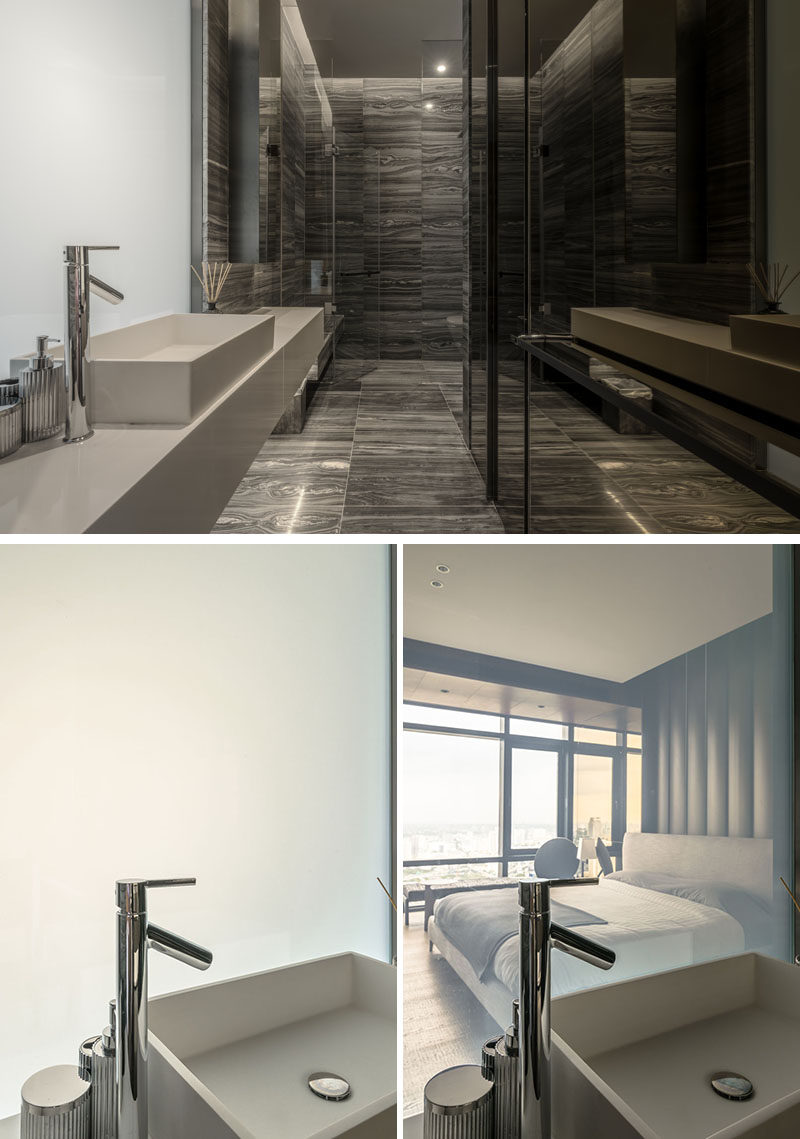 This modern bathroom uses natural stone on the floor and walls, while an opaque glass panel becomes transparent and provides a view of the bedroom. #ModernBathroom #BathroomDesign