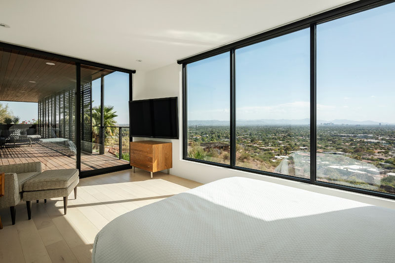 This modern bedroom opens up to a covered patio, while large picture windows perfectly frame the view. #Windows #Bedroom