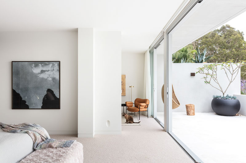 This modern master bedroom opens up to a private balcony that's decorated with a hanging chair and a large round black planter. #MasterBedroom #Balcony #SlidingGlassDoors