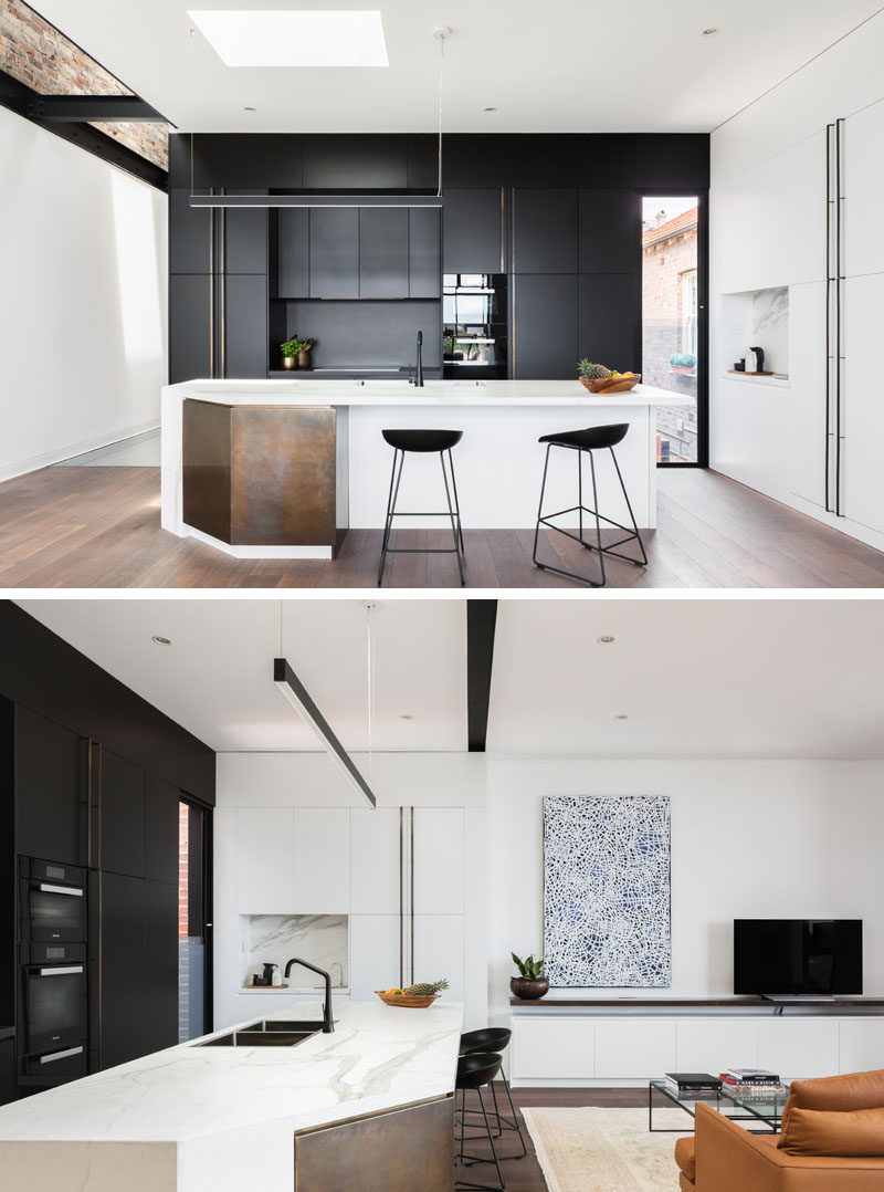In this modern kitchen, black cabinetry lines the wall, while a white island and a section of white cabinetry help to keep the kitchen bright. #BlackAndWhite #Kitchen #ModernKitchen #KitchenDesign
