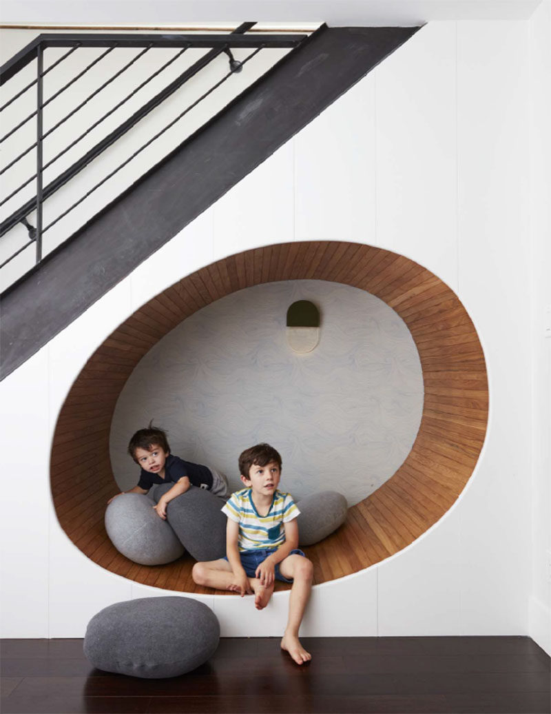 This contemporary townhouse has a wood-lined, built-in curved seating nook under the stairs. #SeatingNook #InteriorDesign