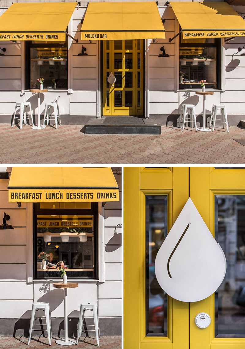 The bright white facade of this modern cafe is highlighted by the use of yellow awnings and a yellow door. #ModernCafeExterior #CafeDesign