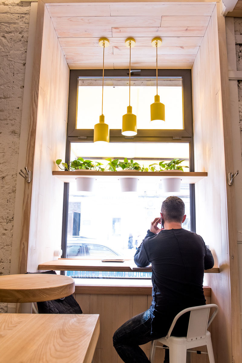 In this modern cafe, bar height counters and stools have been positioned in a window alcove looking out onto the street. #CafeDesign #CoffeeShop #InteriorDesign