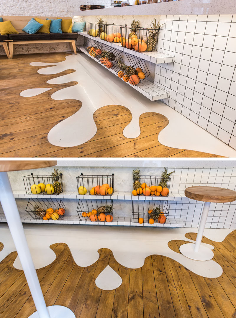 One of the fun elements in this modern cafe is a white 'splash' floor design that connects with the wood floor.  #Flooring #FunFlooring