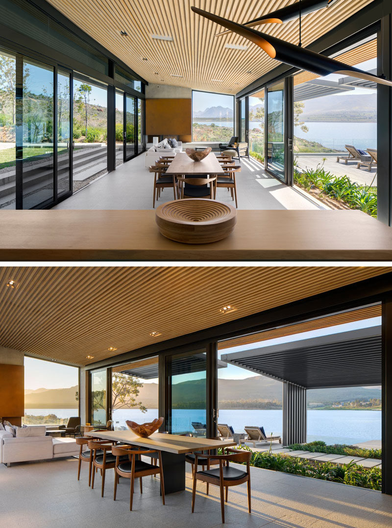 This modern open plan living and dining area opens to the outdoors on both side, while granite covers the floor and wood slats are featured on the ceiling. #DiningRoom #LivingRoom #OpenPlanInterior