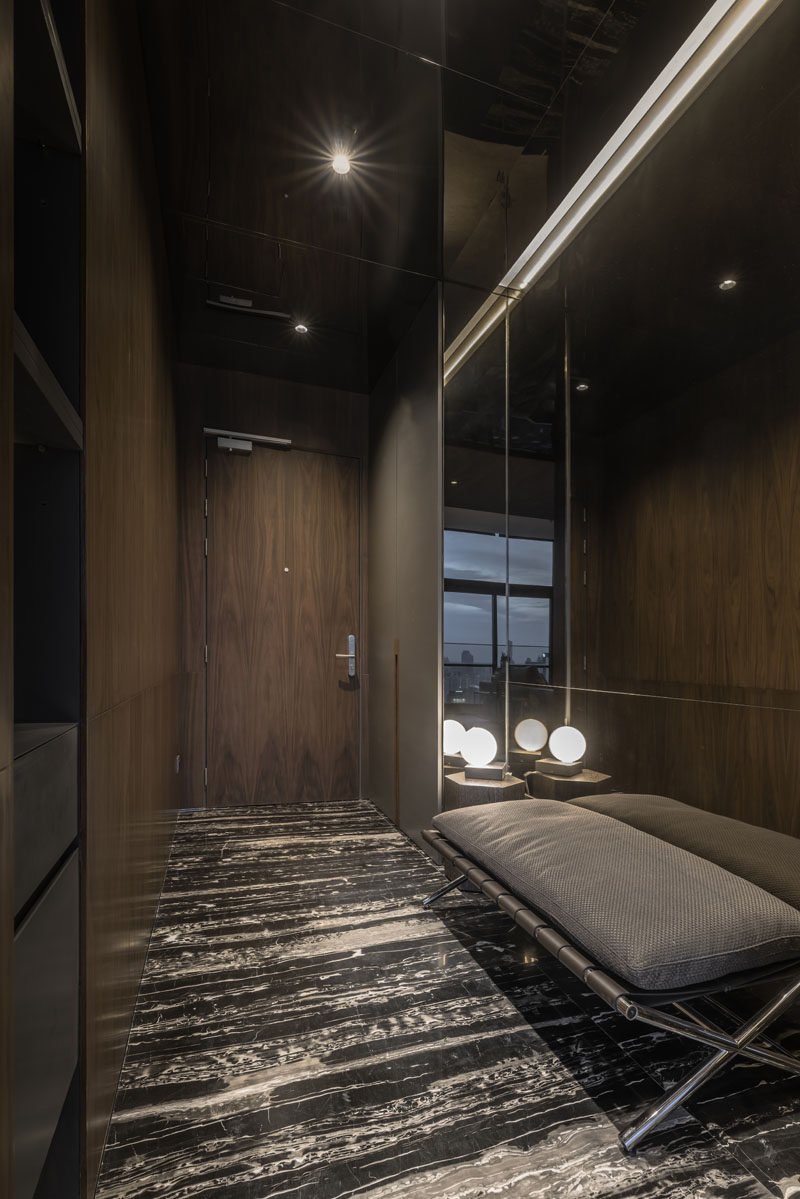 Natural stone, wood, and mirrors have been used throughout the interior of this modern apartment, like in the entryway. #Stone #Entryway #Wood #Mirror