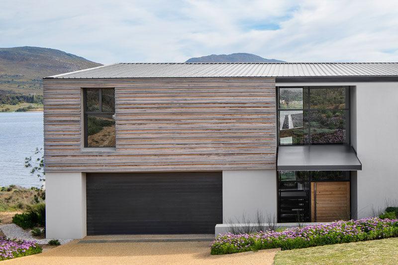 Sections of this modern house are clad in timber, while the roof has been made from corrugated aluminium. The entrance has been designed to be deliberately understated, with a modest canopy sheltering the front door. #ModernHouse #TimberSiding #AluminumRoof