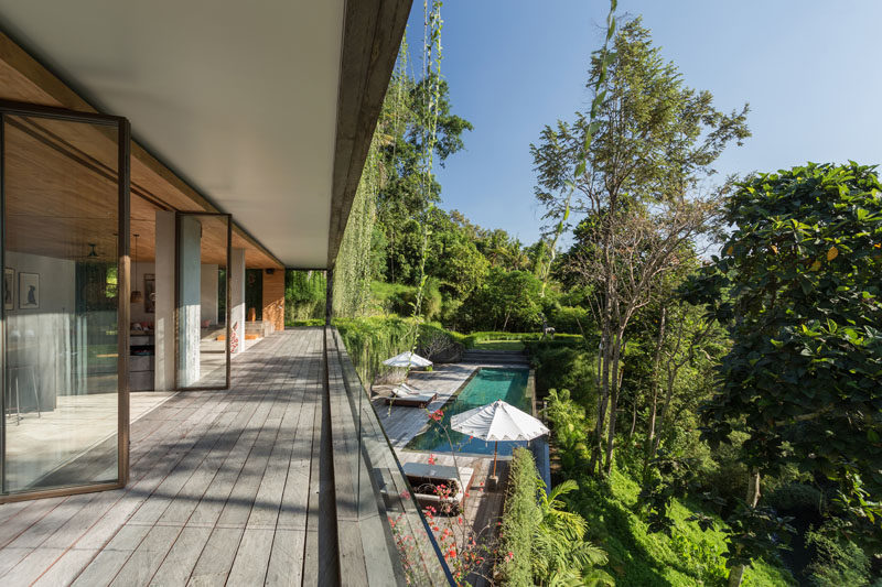 The social areas of this modern house open to a terrace deck that provides an uninterrupted view of the forest, the swimming pool, and the somewhat hidden roof of the building below. #ModernHouse #Deck #SwimmingPool