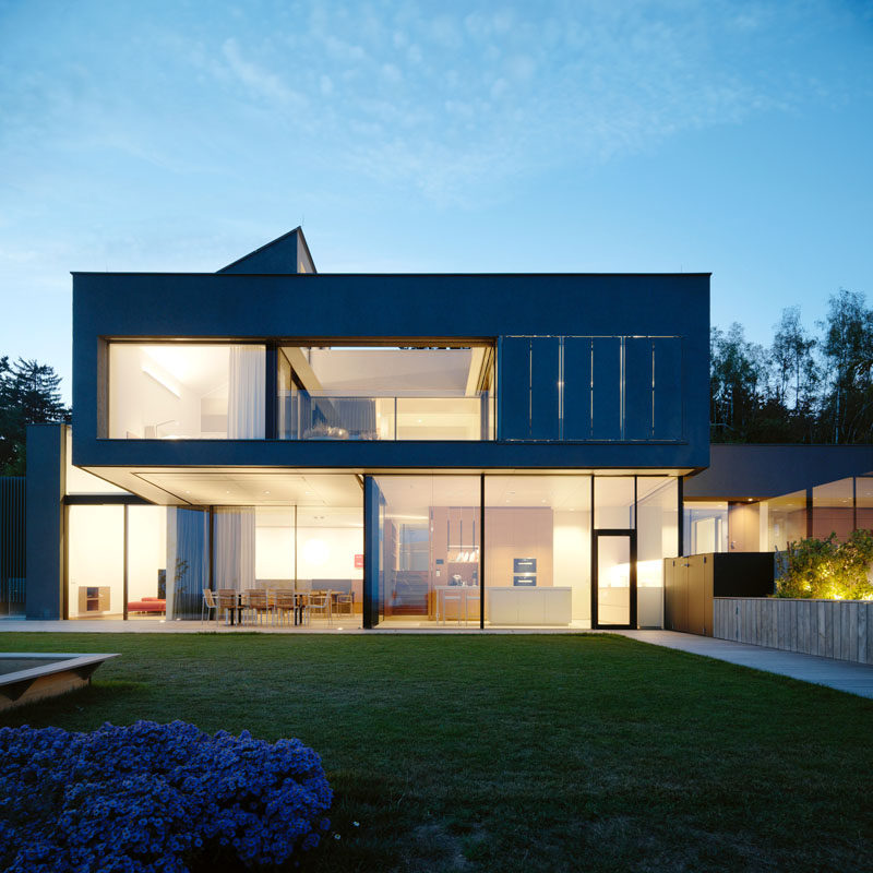 A cantilevered section of the upper floor provides protection for the outdoor dining area of this modern house. #ModernHouse #Windows #Cantilever #Architecture