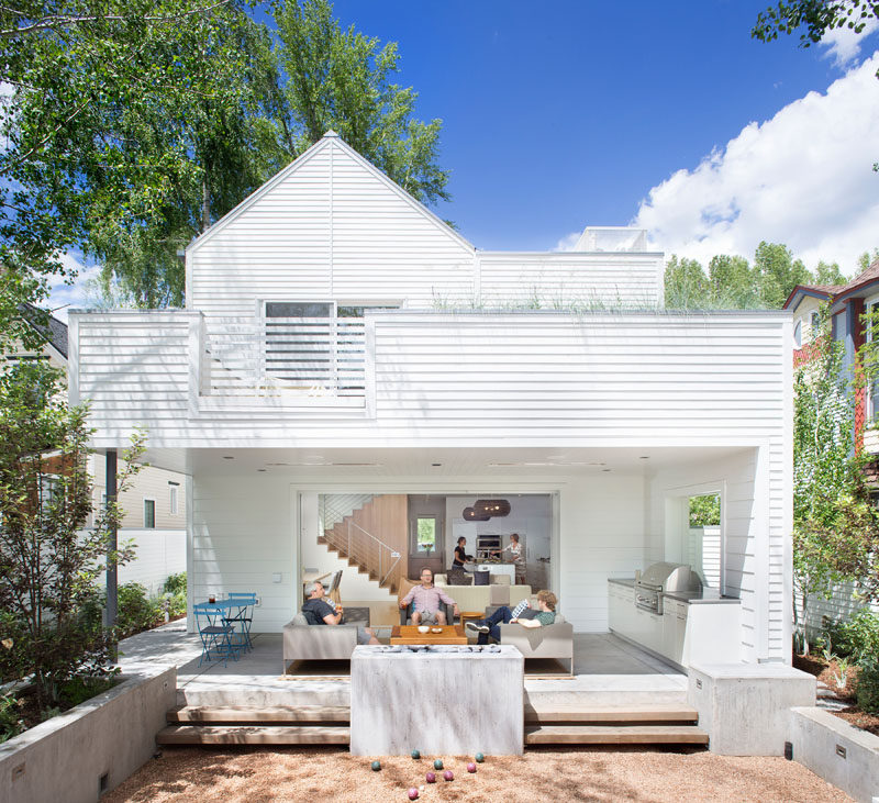 This modern house has a covered outdoor area with a lounge, freestanding fireplace, outdoor kitchen, and a bocce court. #OutdoorSpace #OutdoorEntertaining #OutdoorKitchen