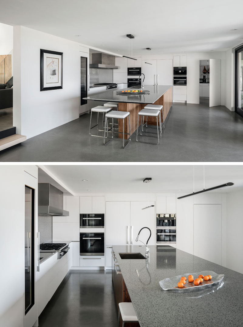 Concrete floors, white and wood cabinets, and quartz counters give this kitchen a modern appearance. #ModernKitchen #KitchenDesign #ConcreteFloors #WhiteKitchen