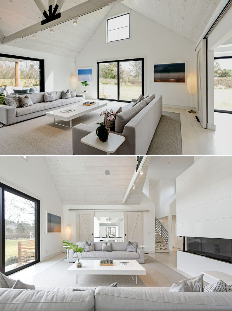 In this modern living room, black window frames and structural support elements contrast the mostly white interior. Sliding barn doors lead to a games room. #ModernBarn #InteriorDesign #LivingRoom #BlackWindowFrames