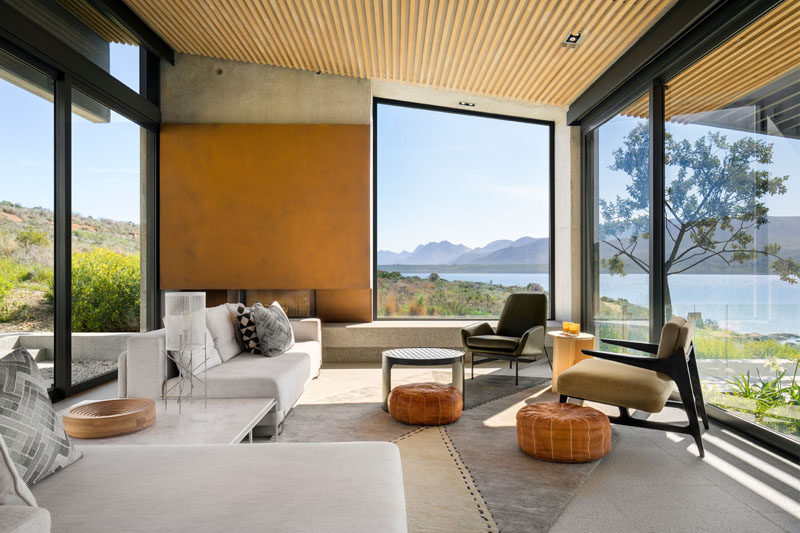 In this modern living room, a fireplace and picture window are framed in a massive concrete hearth wall, and the flues are clad in carefully pre-weathered steel. #LivingRoom #Fireplace #Windows