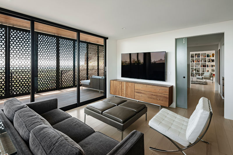 This modern living room opens up to a patio with custom-designed shade screens. #LivingRoom #Patio #ShadeScreens