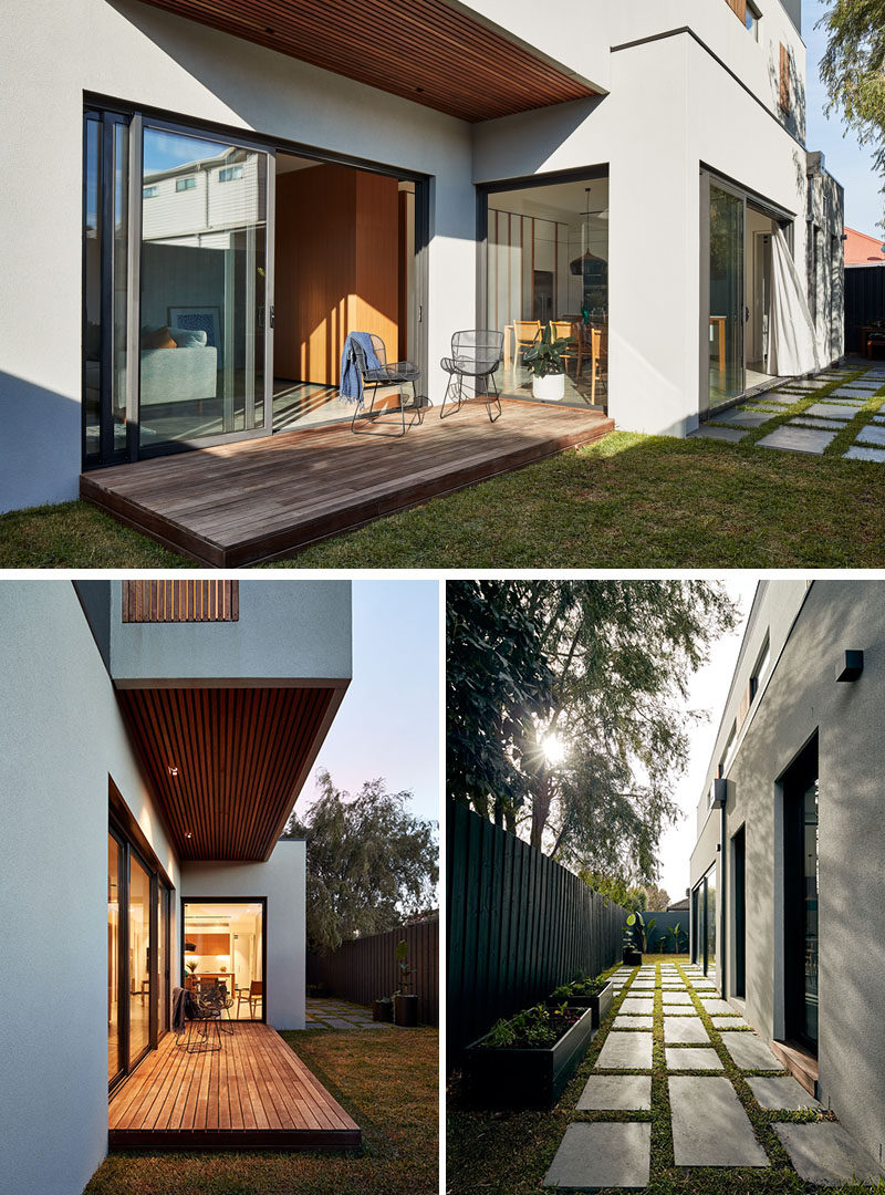 This modern house has a large sliding glass door opens the living room to a small deck, the backyard, and a paved area. #ModernHouse #OutdoorSpace #Landscaping #Deck #Pavers