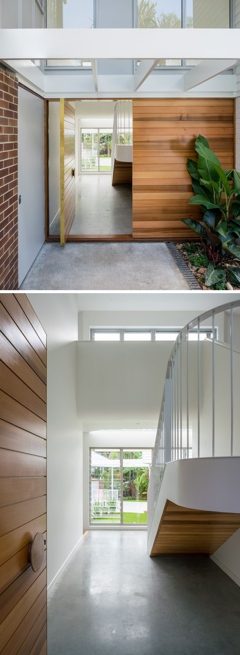 A large pivoting wood front door welcomes visitors to this contemporary home, while inside, there's the stairs leading to the upper floor, and a glimpse of the rear courtyard. #WoodFrontDoor #ModernFrontDoor #Stairs #ConcreteFloor