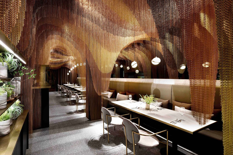 This modern restaurant features approximately 35,000 meters of gold chains that make up sculptural layers, mimicking the mountainous tea fields in China. #RestaurantDesign #ModernRestaurant #MetallicChains #InteriorDesign